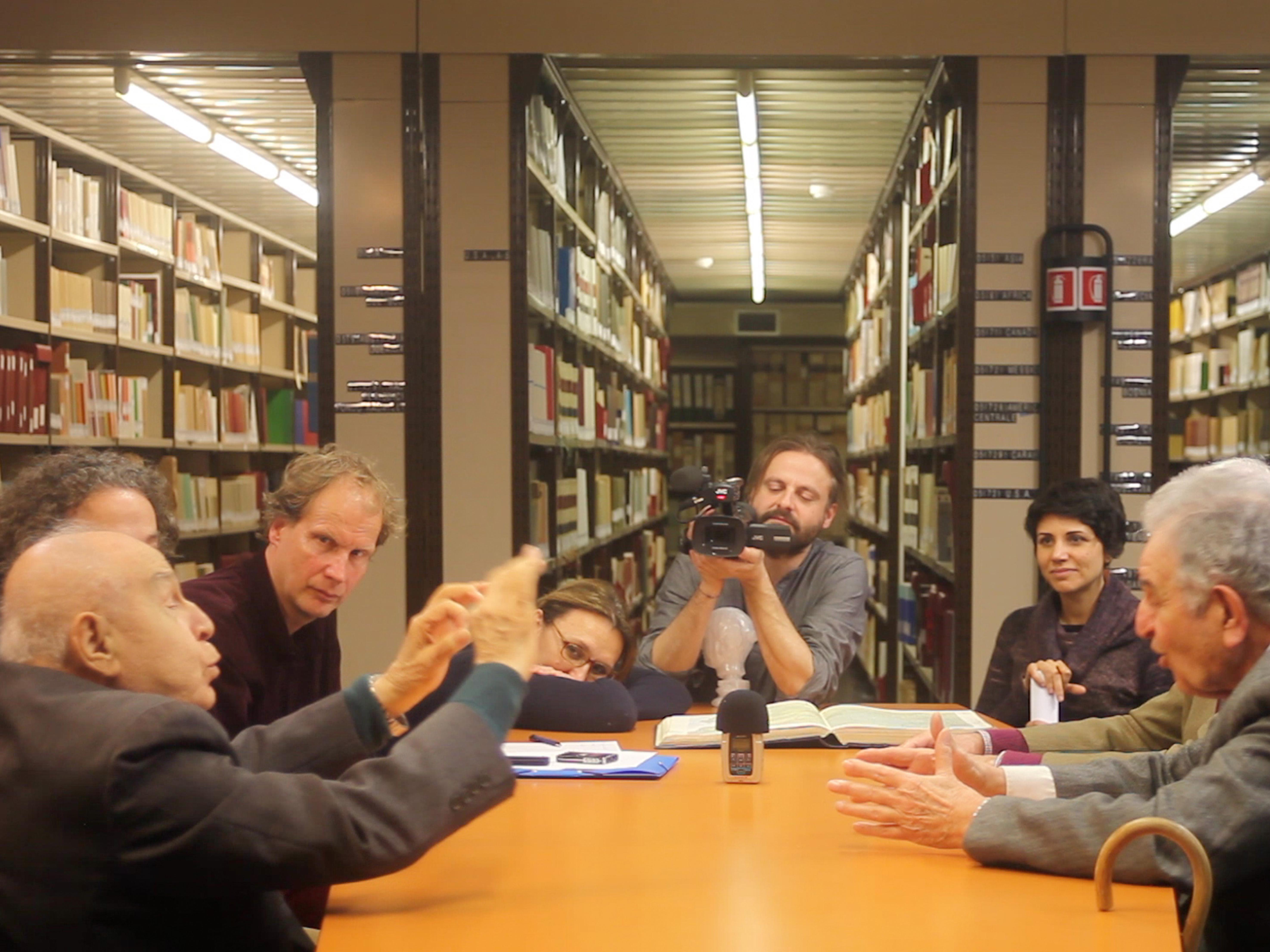 A group of former Italian settlers from Libya interviewed in the library of the Museum L. Pigorini (now Museo delle Civiltà), video still from documentation video,  Rome, (‘Bel Suol D’Amore’ exhibition project, Arnd Schneider /Leone Contini). 2017. Image: Leone Contini.